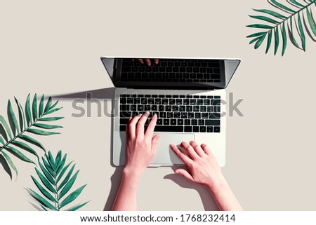 Person using a laptop computer with tropical leaves from above