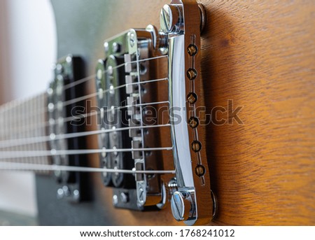 Macro shot of an electric guitar. Strings and bridge. Wooden body of the guitar Music equipment. Metal strings
