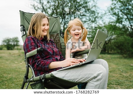 Chat online with family on laptop on picnic in nature. Homeschooling, freelance job. Mom and child. Mother work on Internet with kid outdoors. Quarantine, closed nursery school during coronavirus.