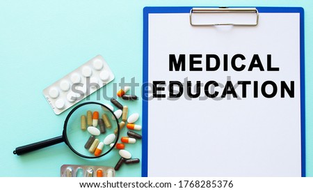 A clipboard with paper lies on a table near drugs and a syringe. Inscription MEDICAL EDUCATION. Medical concept.
