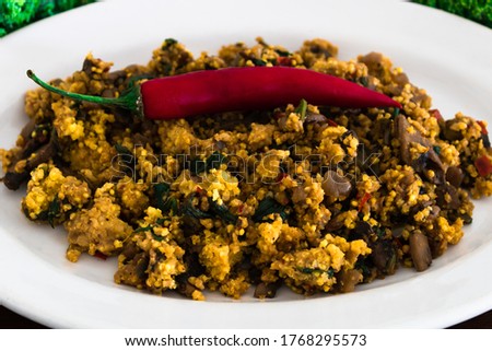 A plate of millet, along with fresh mushrroms, onions, peppers and spices in a close-up form.