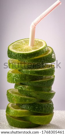 Assortment of slices of green limes, stacked together on top of each other with a straw in it, as a lemonade concept. Royalty-Free Stock Photo #1768305461