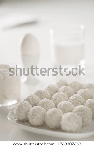 breakfast - milk, eggs, cream cheese and raffaello coconut confectionery on white wood table. white on white picture. Background with free text space
