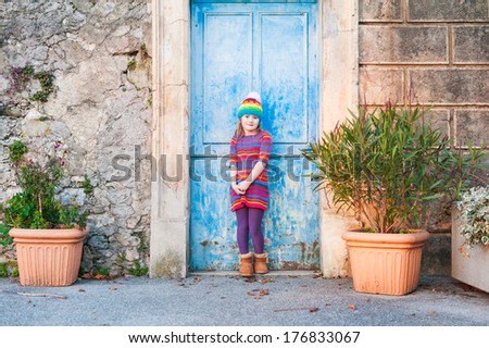 Beautiful little girl in a colorful dress and hat posing outdoors 