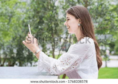 A woman touching and operating the screen of a smartphone outdoors