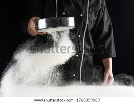baker's hands sift white wheat flour over a sieve over a dark background