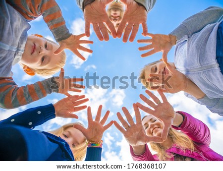 A friendly large family makes a circle shape out of the palms of their hands.
