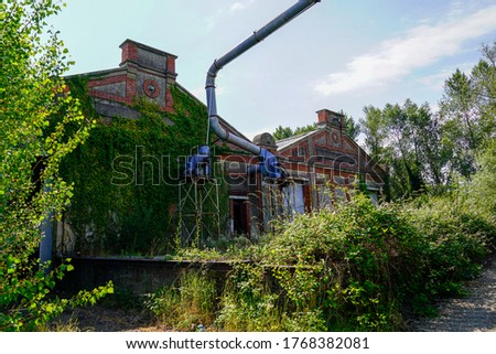 Rusty factory disused abandoned industrial wasteland overgrown with vegetation in France Royalty-Free Stock Photo #1768382081