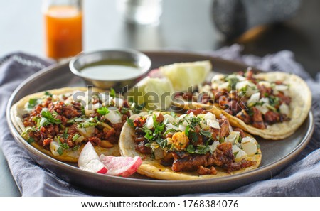trio mexican carne asada tacos in corn tortilla on plate