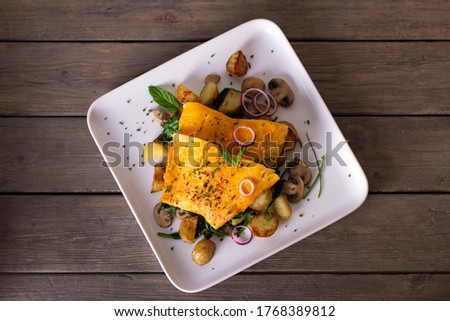 Smoked cod fish fillets with potatoes, mushrooms and spinach. View from above, top studio shot