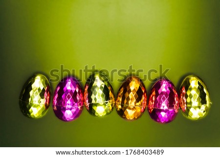 Colorful shiny Easter eggs isolated on green background