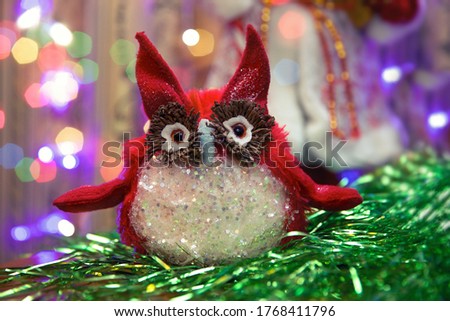 Christmas background, Christmas toy in the form of a red owl with sequins, with colored bokeh in the background