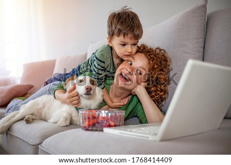 Loving mother resting relaxing with little son together spend free time on weekend have fun using computer. Family surfing internet watch cartoons funny videos making video call