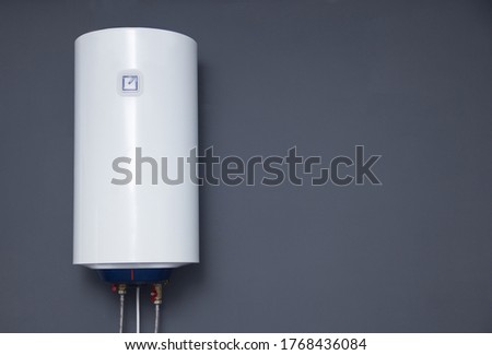 Modern electric boiler on a gray plain wall. White water heater. Space for text Royalty-Free Stock Photo #1768436084