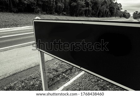 Black and white mockup of traffic sign on the shoulder of a highway with long perspective - Insert your text