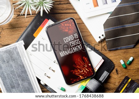 Coronavirus Covid-19 pandemic outbreak Crisis Management background concept. Mockup mobile phone on grunge wood with  business charts, facemask on working table.