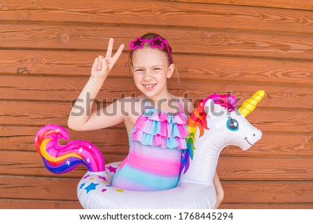 Girl rubber ring unicorn. Wood background. Beach party hot summer.