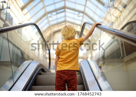 Behavior rules on escalator, in transport, on streets of city. Little child standing on moving staircase. Safety kids. Royalty-Free Stock Photo #1768452743
