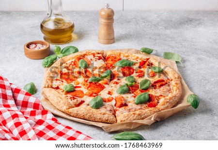 Pepperoni pizza with basil on a light gray background. Top view