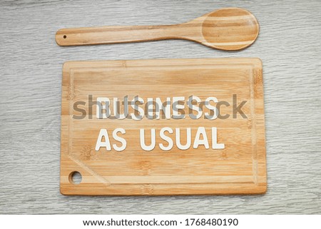 Message on we are open with block letters on wooden chopping board and a wooden spoon 