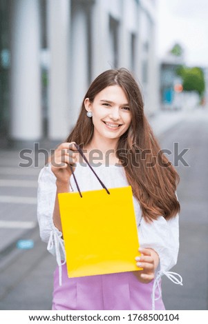 Young woman holding a paper bag with presents with a smile