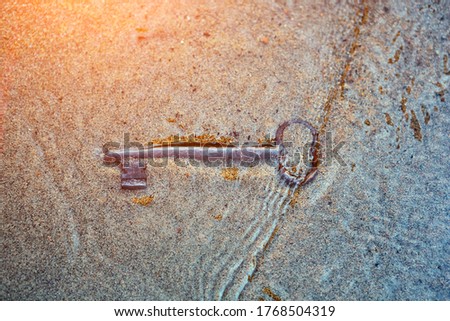 The sea washed up on the sandy beach an old vintage key to a treasure chest. The concept of success, luck and wealth