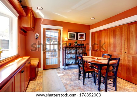 Cozy and bright dining room with beige concrete floor and wooden cabinets. Antique style black dining table set and glass door cabinet