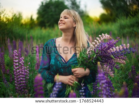 A girl in a Lupin field at sunset. Girl with a bouquet.