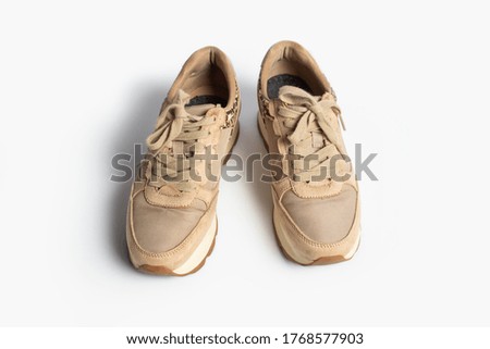 Women's beige sneakers with laces on a light background. Flat lay, top view