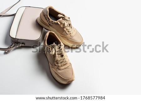 Sneakers and cross body bag on a light background. Accessories for a fashionable look. Flat lay, top view