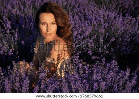 
A beautiful young girl enjoys the sun in the middle of lavender fields. Provence girl. Summer mood.