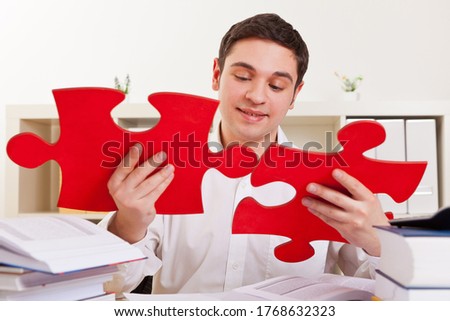 Businessman in the office puts together two large red puzzle pieces