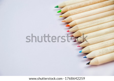 Macro photography of colorful pencils on the right side with copy space for text on left side. Back to school concept with multicolored crayons. Wallpaper with stationery light lavender background.