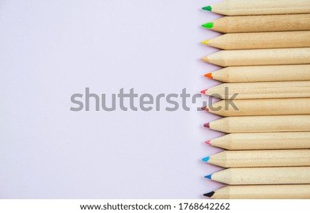 Close up picture from top view of colorful pencils on the right side with copy space for text. Back to school concept with multicolored crayons. Wallpaper with stationery avender background.