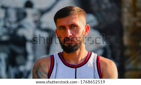 A basketball player with beard in jersey staring on basketbal picture background