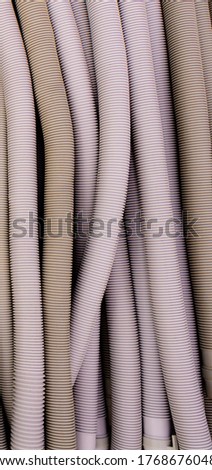 Corrugated Pipe concept for posting pipe as background, wallpaper.
Close up a row of grey plastic drainages, gas, and water pipes cable protection in electrical installation.