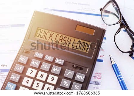 written text quick cash loan in calculator on office table with glasses and pen. Business and banking concept