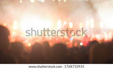 crowd at concert - summer music festival in front of bright stage lights. Dark background, smoke, concert spotlights.people dancing and having fun in summer festival party outdoor