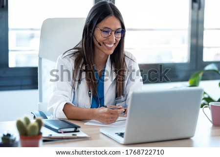 Shot of female doctor talking with colleagues through a video call with a laptop in the consultation. Royalty-Free Stock Photo #1768722710