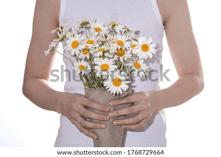 the boy holds a bouquet of daisies in his hands, his son gives his mother a wildflowers, rustic bouquet