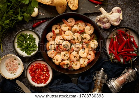 Tasty shrimp tails fried in butter with, garlic, parsley, white wine and chili. With various ingredients on sides. Home seafood concept. Top view, flat lay.