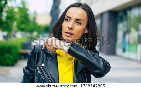 New modern technologies! A half-length photo of a young businesswoman on the street, that possesses a smartwatch, smartphone, wireless headphones.