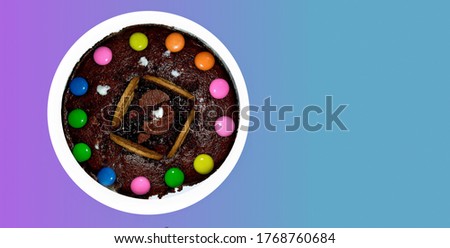 Top view of home made cake, decorated with candies and biscuit, isolated on colorful background with copy space.