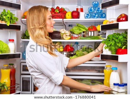 Woman chosen milk in opened refrigerator, cool new fridge full of tasty organic nutrition, female preparing to cook, healthy eating concept Royalty-Free Stock Photo #176880041