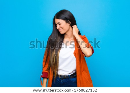 young pretty latin woman feeling stressed, frustrated and tired, rubbing painful neck, with a worried, troubled look against flat wall