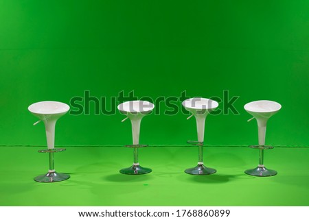 White 4 studio Chairs are settled in front of a green screen in studio light around.