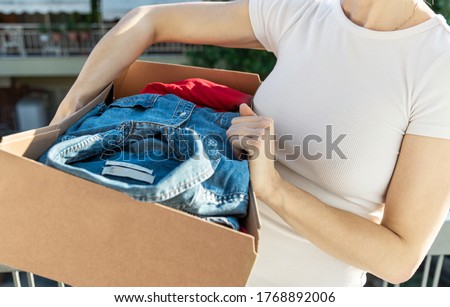 Woman holding card box with clothes. Donation concept