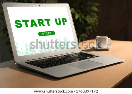 Modern laptop and cup of coffee on desk in office. Startup idea