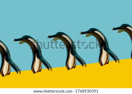 Funny black banana in the shape of a penguin on a yellow background. Concept for summer, tanning, parties.