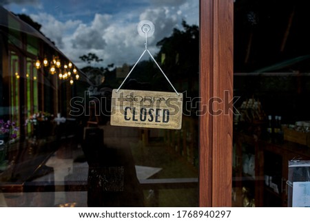 Closed for holiday. Sorry we are closed red circle round tag hanging on a glass of storefront.